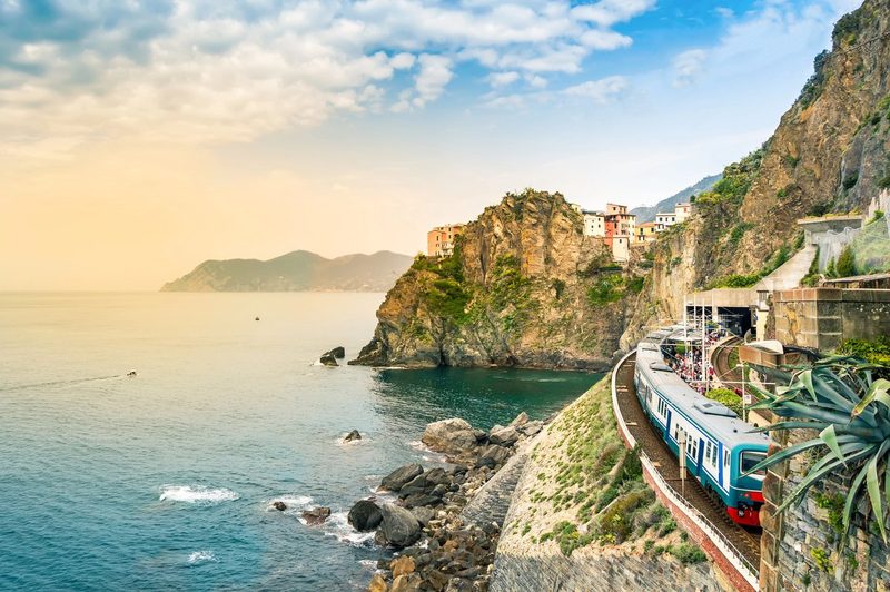 Un train régional bleu en gare de Manarola, village perché sur les falaises des Cinque Terre face à la mer Ligure au coucher du soleil