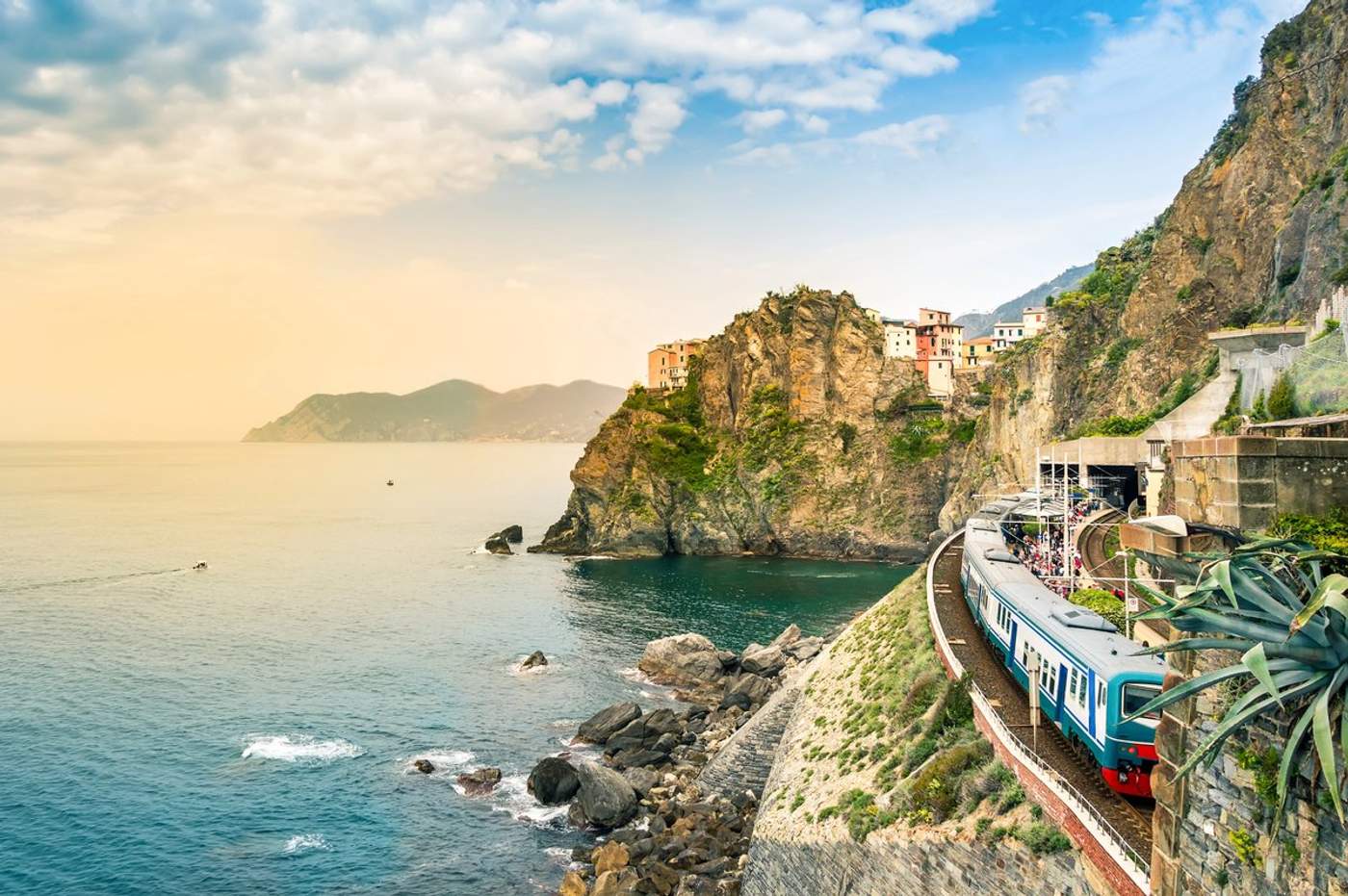 Un train régional bleu en gare de Manarola, village perché sur les falaises des Cinque Terre face à la mer Ligure au coucher du soleil