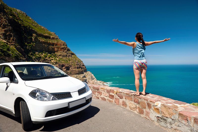 Femme bras écartés devant la mer, arrêtée en bord de route lors d