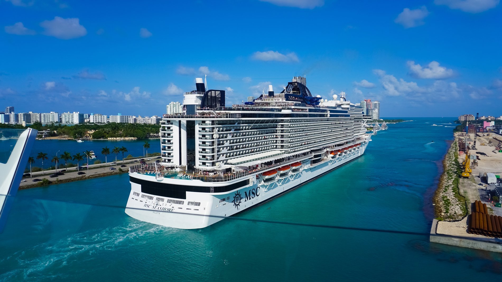Navire de croisière MSC Seashore quittant le port de Miami par temps ensoleillé, avec les gratte-ciel en arrière-plan et les eaux turquoise.