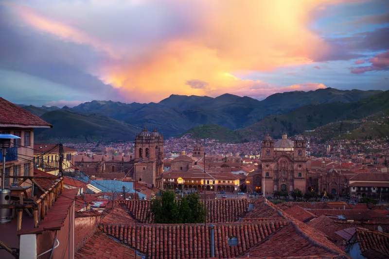 Vue panoramique de Cusco au coucher du soleil avec la cathédrale et les toits rouges face aux montagnes des Andes