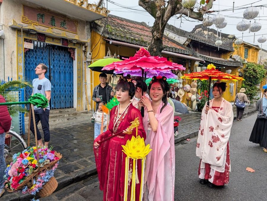 Défilé de femmes en costume traditionnel dans les rues de Hoi An