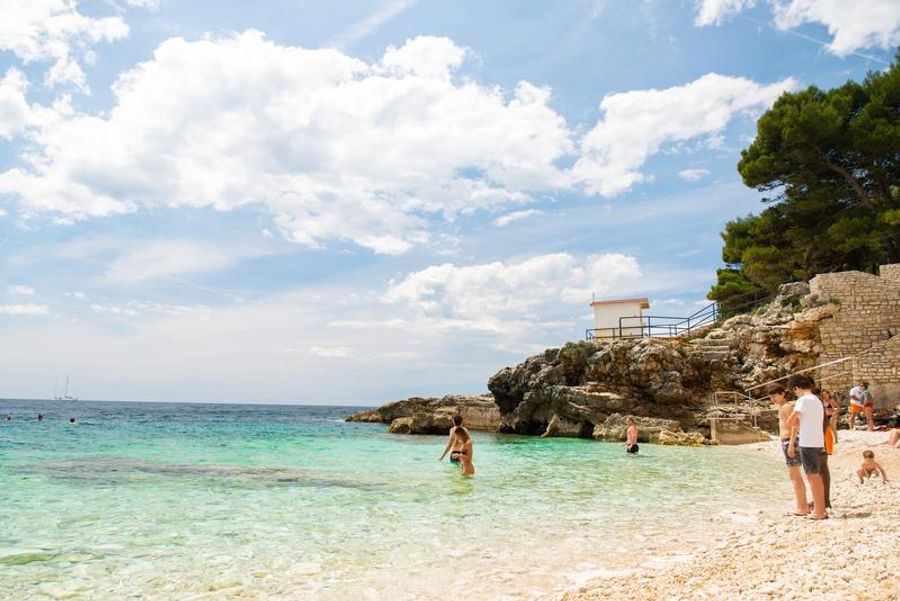 Une plage avec des eaux cristallines et un ciel dégagé à Pula.