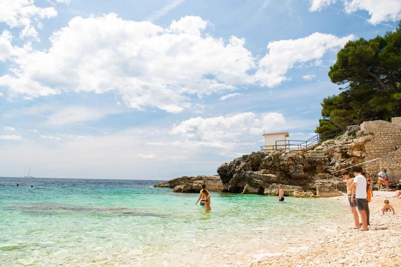 Une plage avec des eaux cristallines et un ciel dégagé à Pula.