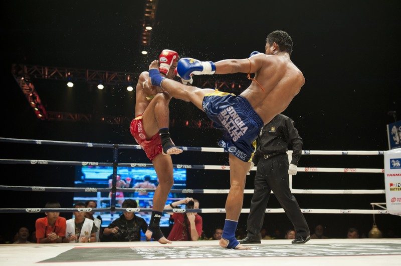Combat intense de Muay Thaï dans un stade.