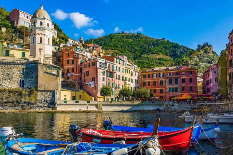 Vue pittoresque de Cinque Terre en Italie avec des maisons colorées et des bateaux amarrés sur l'eau.