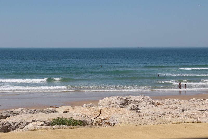 Une plage de sable à Costa da Caparica, Portugal, avec des baigneurs et des surfeurs dans l
