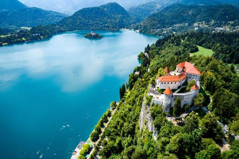 Vue aérienne du château de Bled perché sur sa falaise dominant le lac Bled et son île avec l'église de l'Assomption, Slovénie