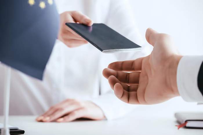 Agent de contrôle remettant un passeport à un voyageur à un comptoir administratif.