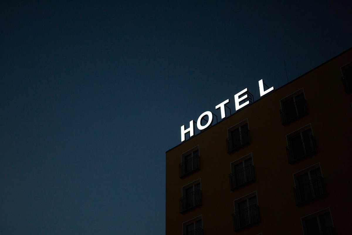 Façade d’un hôtel de nuit avec enseigne lumineuse « HOTEL » sur fond de ciel sombre