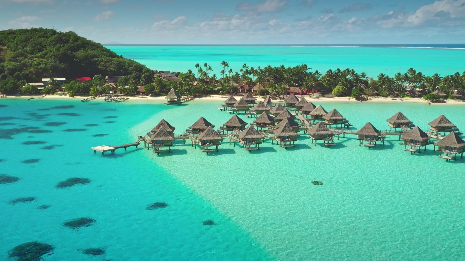 Vue aérienne de luxueux bungalows sur pilotis entourés d'un lagon turquoise à Bora Bora, en Polynésie Française. Un cadre paradisiaque idéal pour un séjour de rêve.