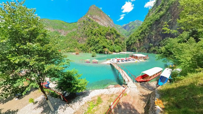 Lac de Komani en Albanie avec eau turquoise, pontons en bois et montagnes verdoyantes