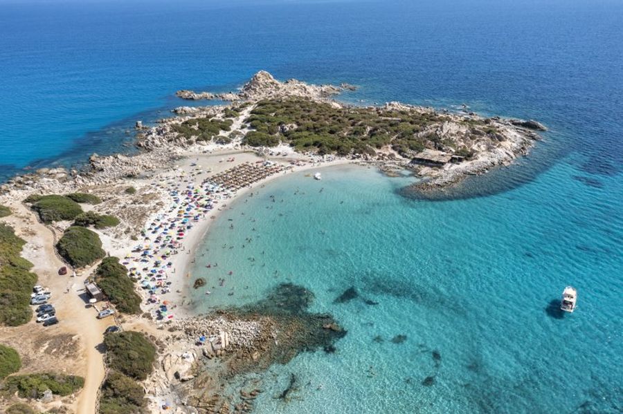 Plage de Punta Molentis avec eaux turquoise et parasols colorés.