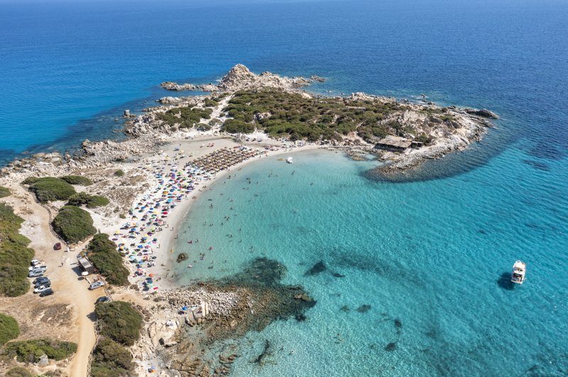Plage de Punta Molentis avec eaux turquoise et parasols colorés.