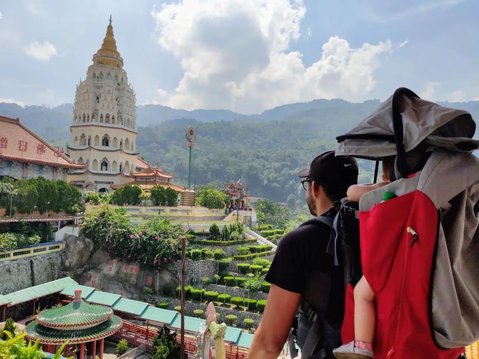 Cyril et Anna dans son porte-bébé de randonnée observant un temple en Malaisie