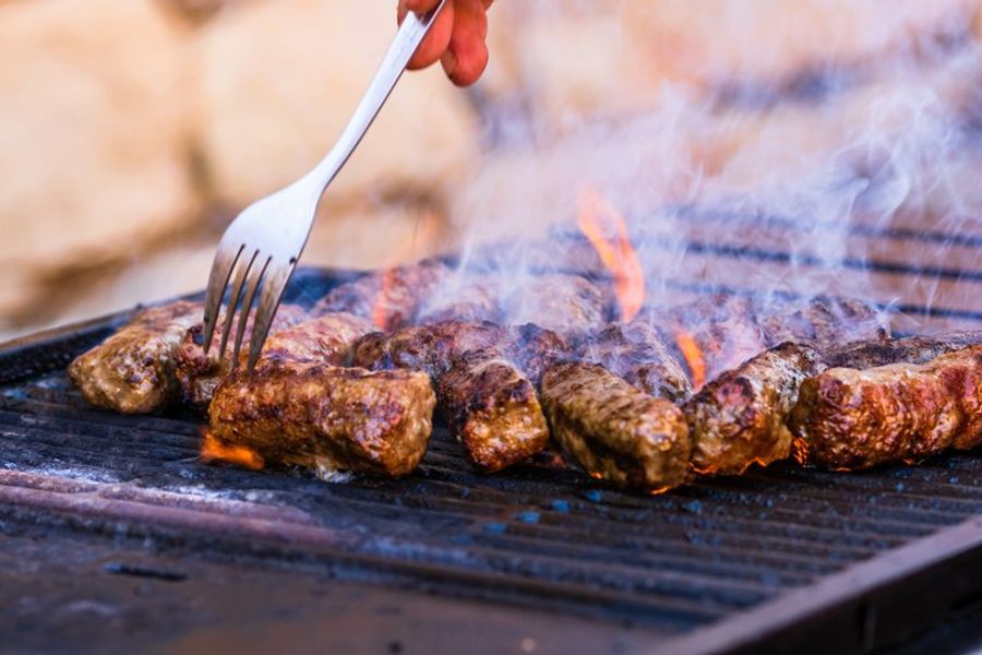 Barbecue avec des mici grillés émettant de la fumée.