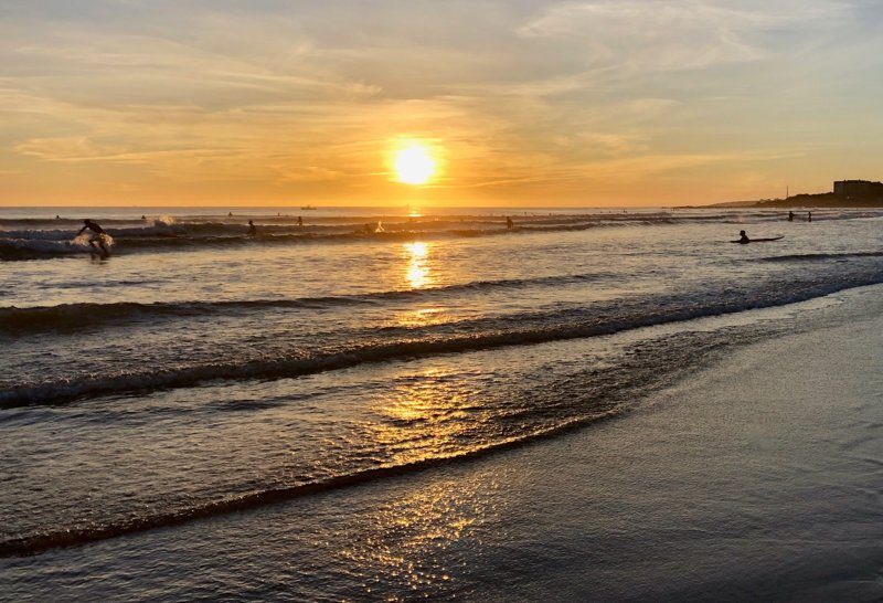 Plage de Carcavelos à Carcavelos, Portugal, avec des surfeurs et des vacanciers profitant de la mer et du soleil.