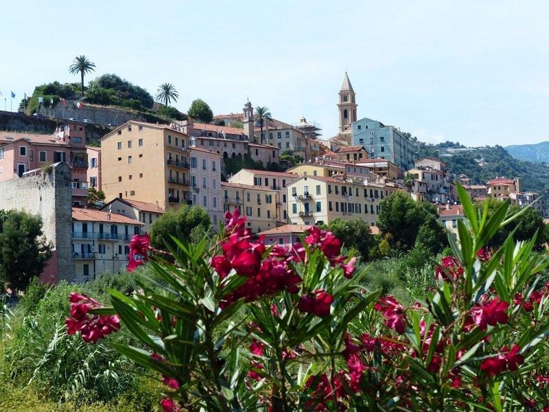 Vue aérienne de Ventimiglia en Italie, montrant le village entouré de collines et la rivière traversant la vallée.