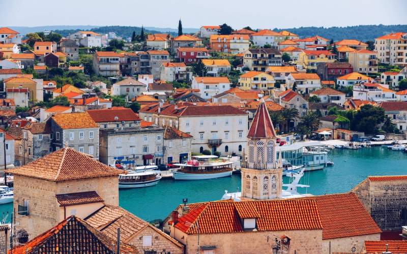 Vue panoramique sur les toits de la vieille ville de Trogir avec des maisons en pierre et des bateaux dans le port, Croatie.