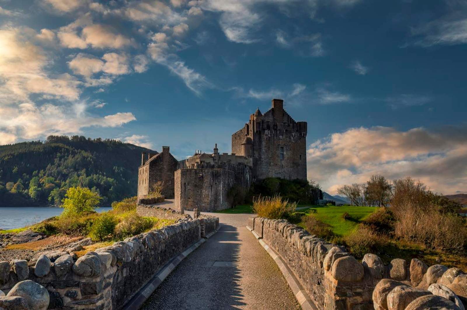 Château d’Eilean Donan accessible par un pont de pierre, au bord d’un loch dans les Highlands d’Écosse