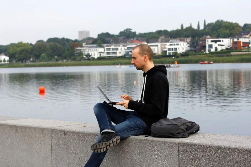 Un digital nomad travaillant sur son ordinateur portable au bord d'une rivière