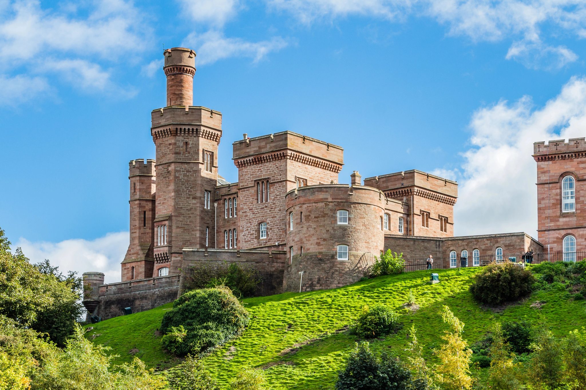 Façade du château d’Inverness en pierre rose sur sa colline herbeuse