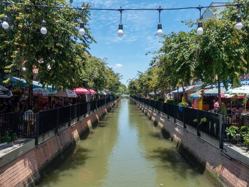 Vue du canal Ong Ang avec des stands de marché et des arbres.