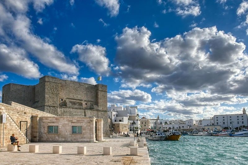 Vue extérieure du Castello di Carlo V à Monopoli, un château historique avec un ciel partiellement nuageux en arrière-plan.
