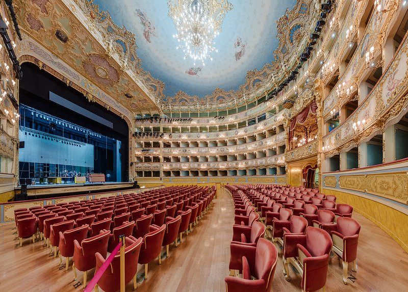 Intérieur du Théâtre de la Fenice à Venise, avec ses sièges rouges et son plafond orné.
