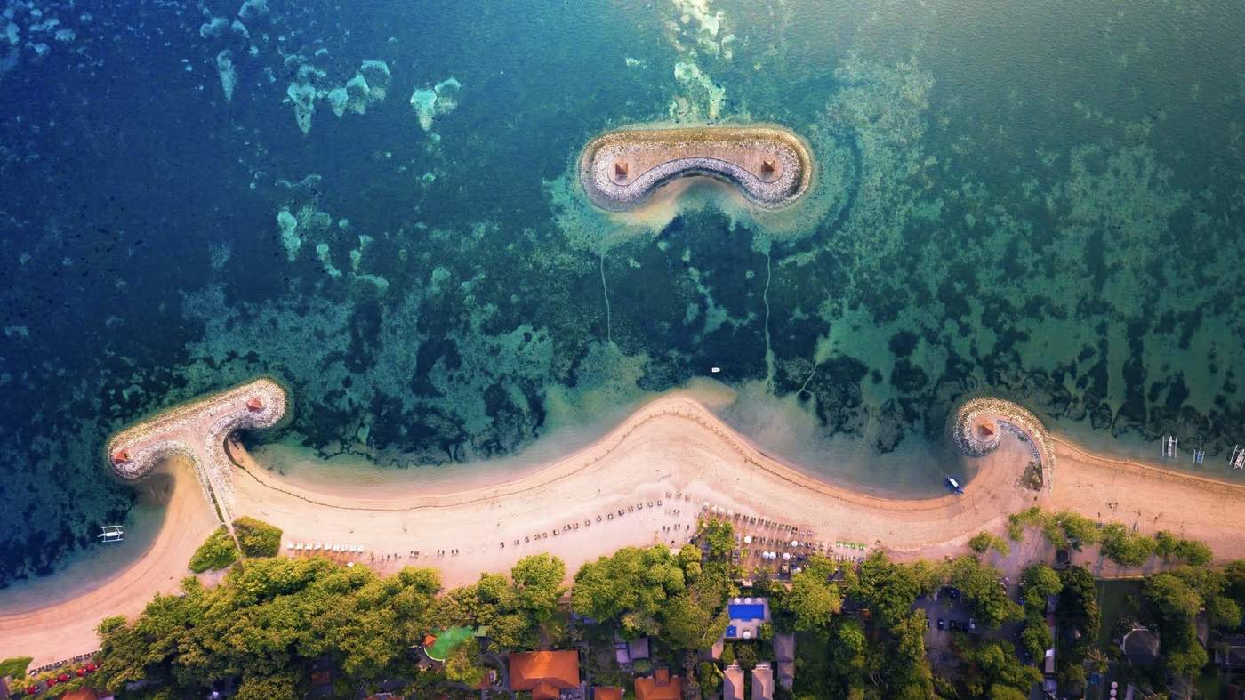 Vue aérienne des plages de Sanur, Bali, avec les récifs et les huttes en bord de mer.