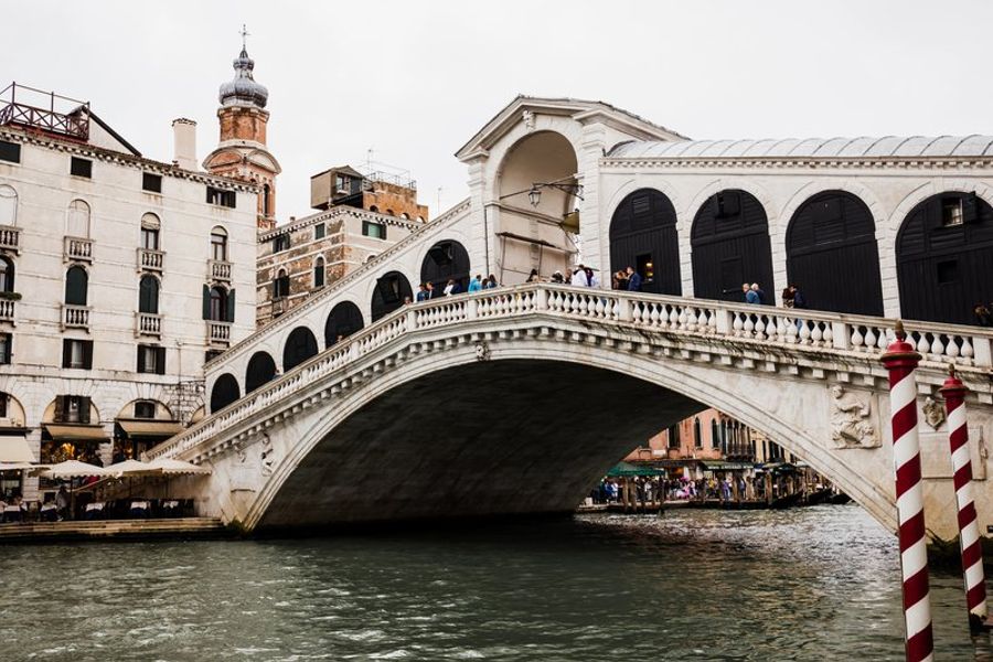 Le célèbre pont du Rialto à Venise vu depuis le canal, avec des passants et bâtiments anciens