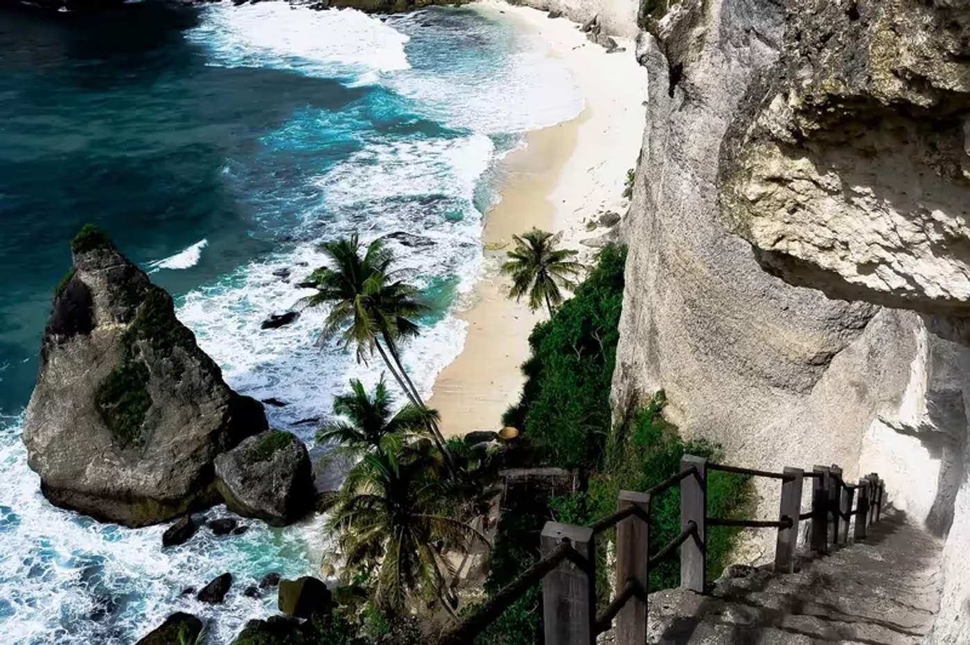 Falaises spectaculaires de Nusa Penida surplombant une plage isolée aux eaux turquoise.