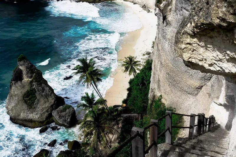 Falaises spectaculaires de Nusa Penida surplombant une plage isolée aux eaux turquoise.