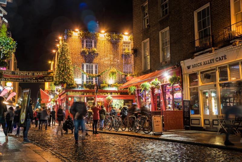 Vue nocturne animée du quartier de Temple Bar à Dublin, avec des lumières festives et des passants appréciant la vie nocturne.