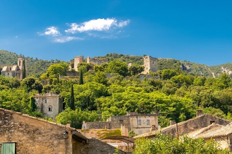 Charmant village de Goult avec ses ruines médiévales et ses bâtiments en pierre entourés de verdure.
