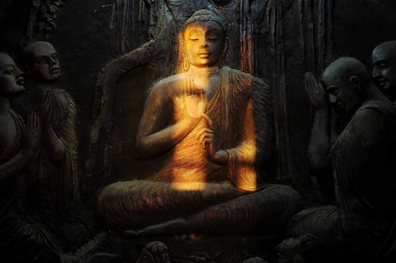 Relief sculpté représentant Bouddha en méditation, éclairé par une lumière dorée, à Kandy au Sri Lanka.