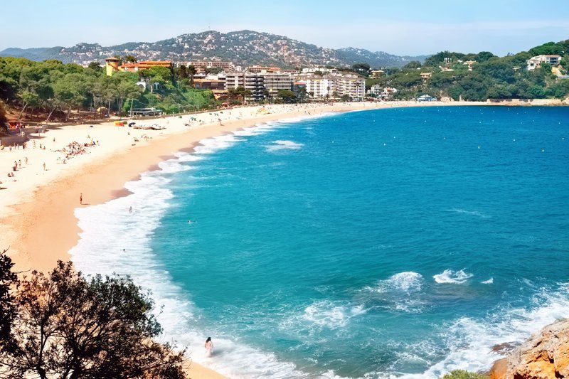 Vue panoramique de la plage de Lloret de Mar, entourée de bâtiments et d’une mer turquoise