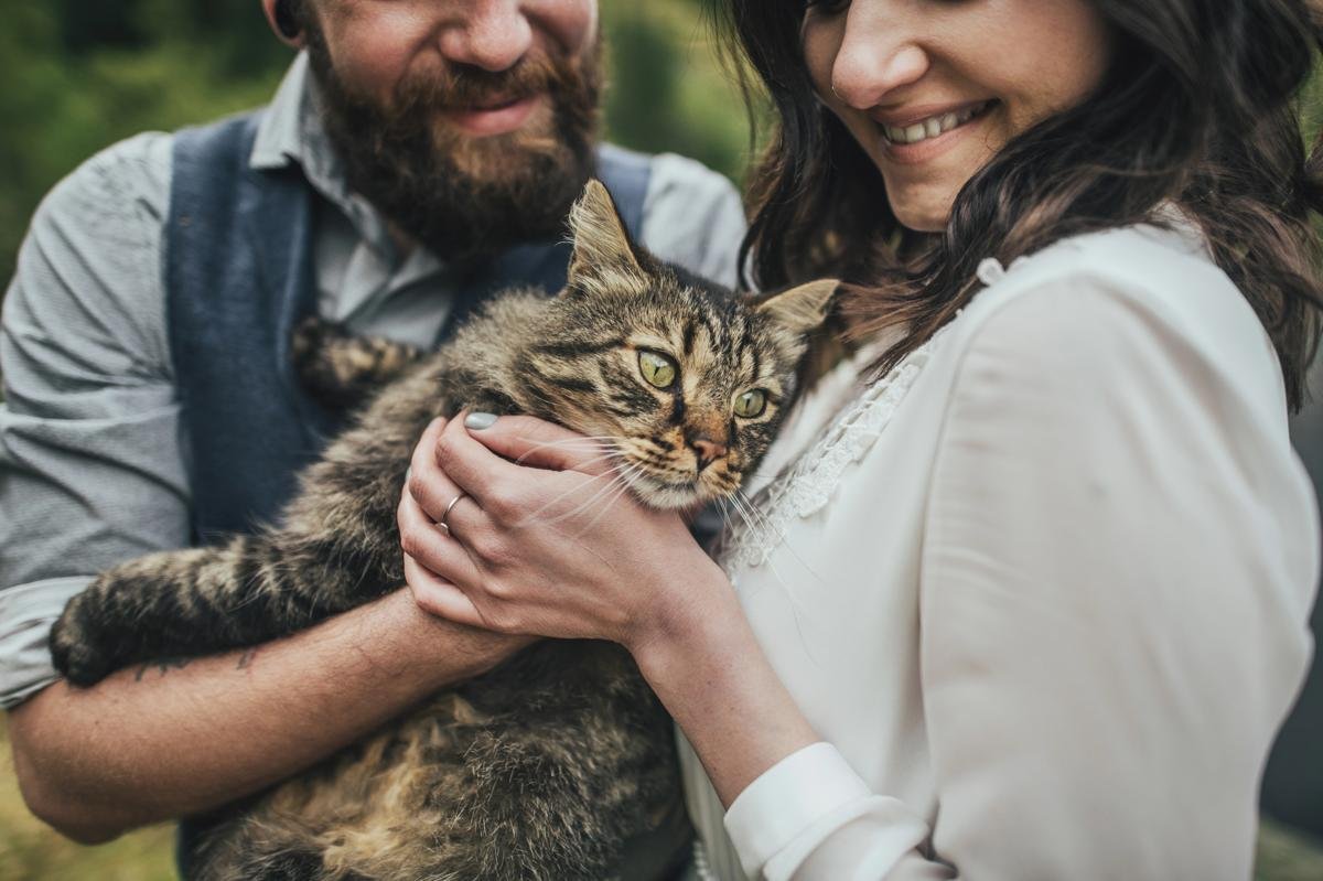 Couple souriant tenant un grand chat tigré dans les bras, moment tendre en extérieur