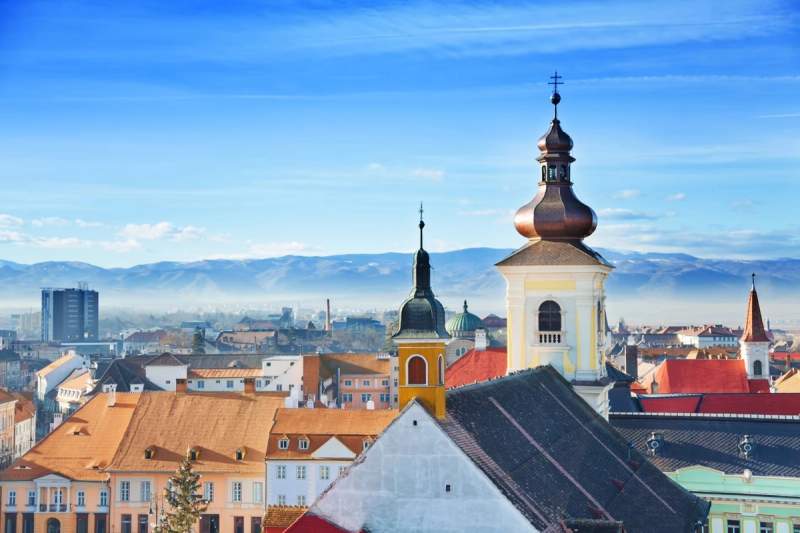 Vue panoramique sur Sibiu, Roumanie, avec montagnes en arrière-plan sous un ciel bleu.