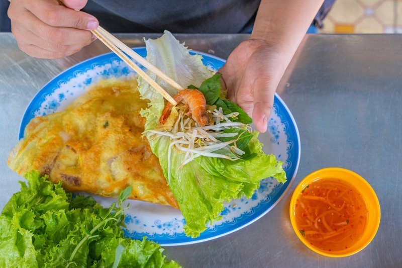 Plat de bánh xèo vietnamien croustillant garni de crevettes, germes de soja et herbes fraîches