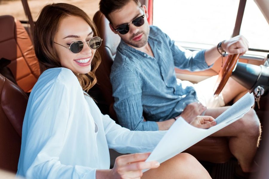 Couple assis dans une voiture consultant une carte pendant un road trip