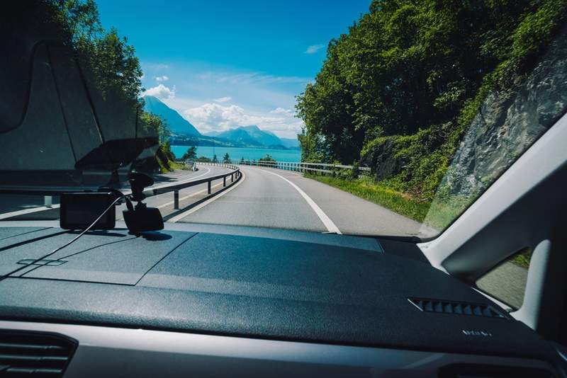 Vue depuis une voiture lors d’un road trip au bord d’un lac de montagne en France sous un ciel bleu
