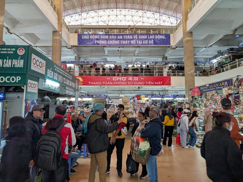 ntérieur du marché Dong Xuan à Hanoï avec foule et stands variés.