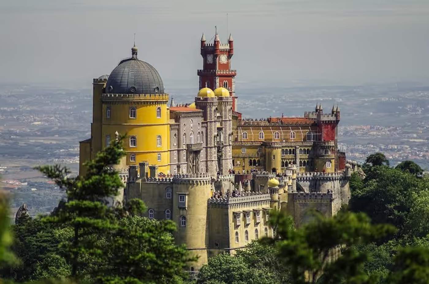 Vue sur le Palais de Pena avec ses couleurs vives et ses tours, entouré de végétation à Sintra, Portugal.