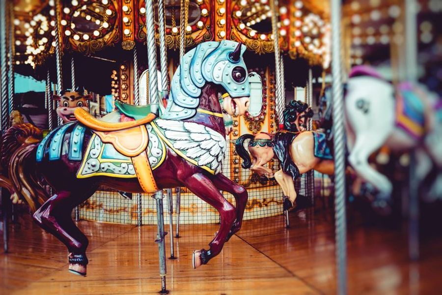 Cheval de manège coloré avec des détails ornés, entouré de lumières scintillantes sur un carrousel à Luna Park à Fréjus.