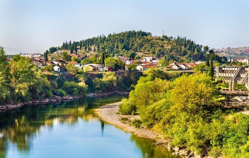Vue de la rivière Morača traversant Podgorica avec les collines verdoyantes en arrière-plan au Monténégro.