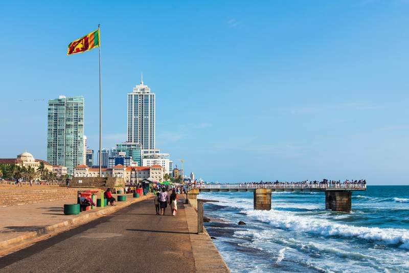 Promenade en bord de mer à Galle Face Green avec drapeau sri-lankais et skyline.