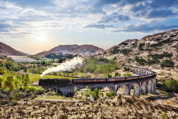 Le train à vapeur Jacobite traverse les arches du viaduc de Glenfinnan, avec les collines et le Loch Shiel à l’arrière-plan