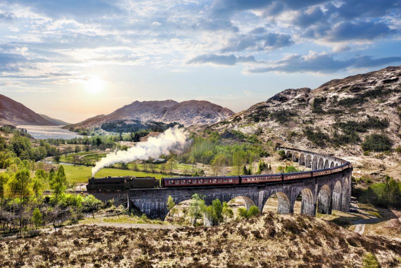 Le train à vapeur Jacobite traverse les arches du viaduc de Glenfinnan, avec les collines et le Loch Shiel à l’arrière-plan