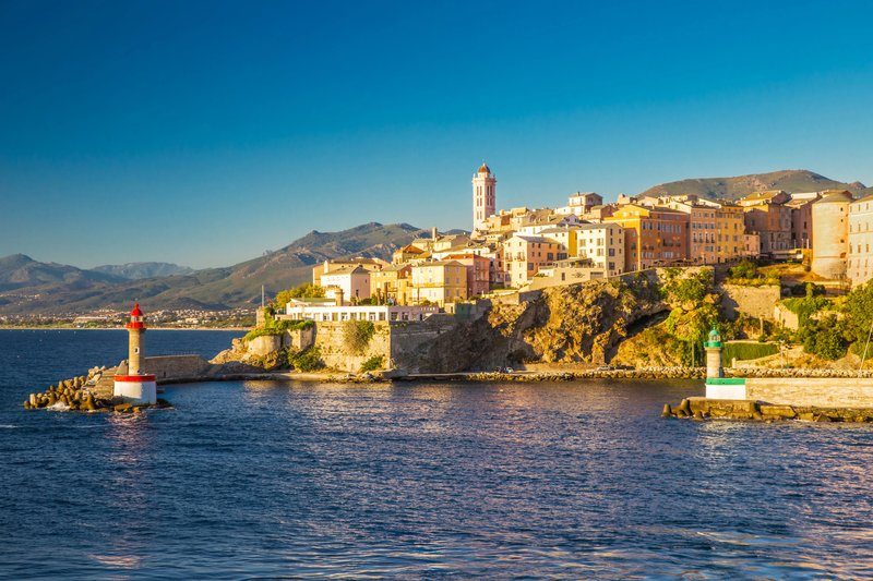 Vue sur le vieux port de Bastia en Corse, avec ses bâtiments colorés au coucher du soleil.